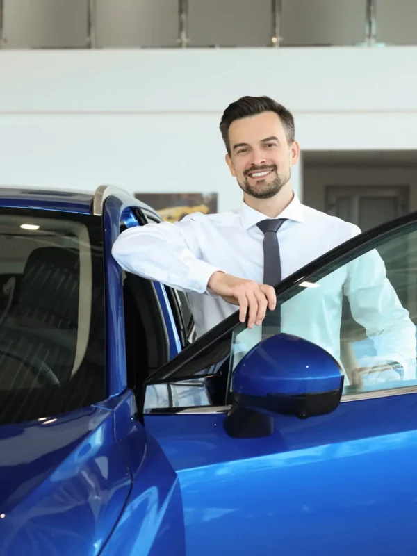 Happy man near new blue car in salon Happy man near new blue car in salon
